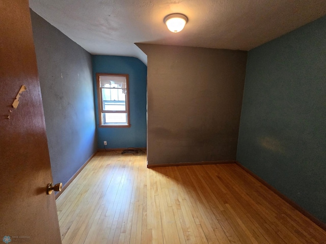 bonus room featuring light wood-type flooring and a textured ceiling