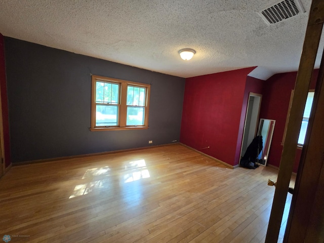 empty room with a textured ceiling and light hardwood / wood-style floors