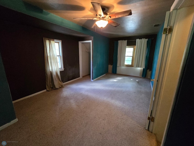 unfurnished bedroom featuring light carpet, ceiling fan, and a closet