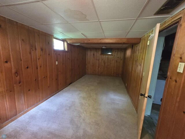 basement with a paneled ceiling and wood walls