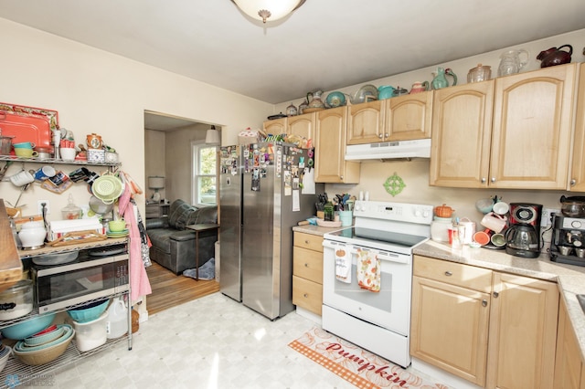 kitchen with light brown cabinetry, stainless steel refrigerator, and electric stove