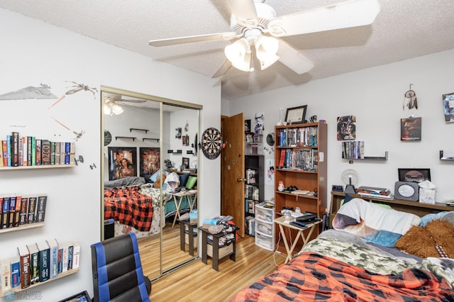 bedroom with a closet, hardwood / wood-style flooring, a textured ceiling, and ceiling fan