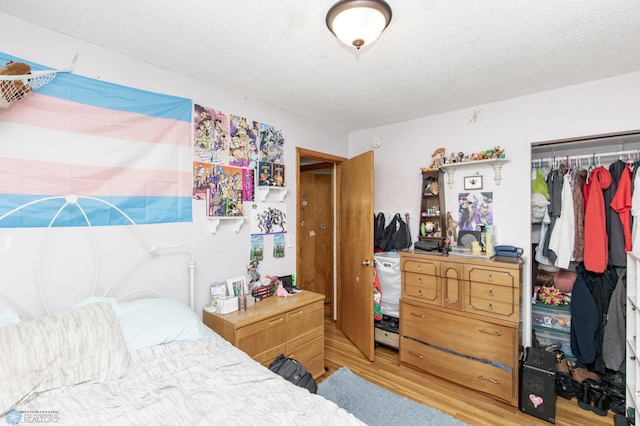 bedroom with a textured ceiling, a closet, and light hardwood / wood-style flooring