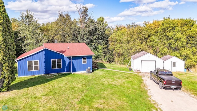 view of front of house featuring central AC unit, a garage, a front lawn, and an outbuilding