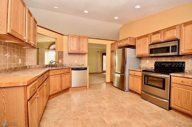 kitchen with decorative backsplash, vaulted ceiling, sink, and stainless steel appliances