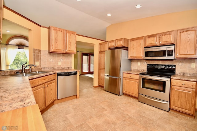 kitchen with lofted ceiling, appliances with stainless steel finishes, and backsplash