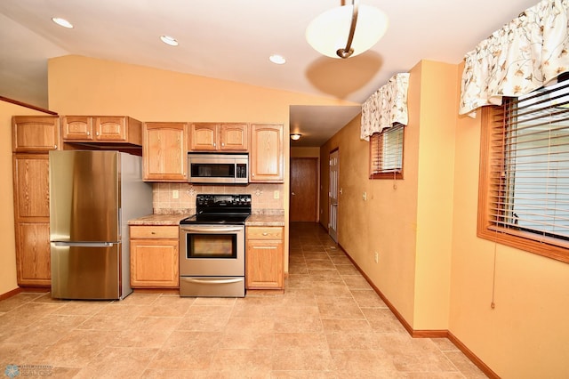 kitchen with light brown cabinetry, appliances with stainless steel finishes, backsplash, and lofted ceiling