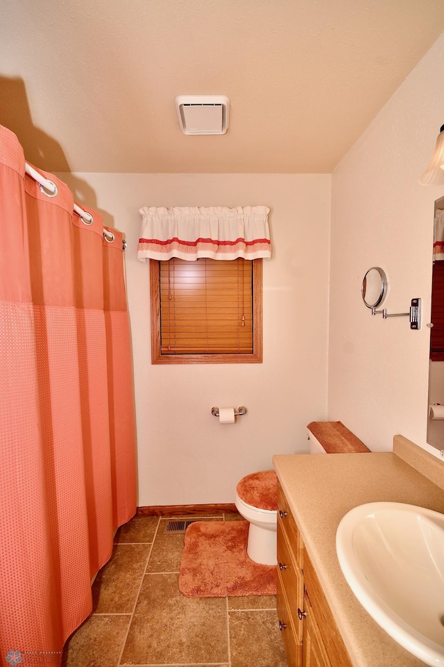 bathroom with walk in shower, vanity, tile patterned flooring, and toilet