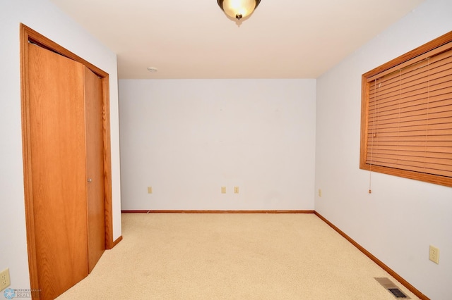 unfurnished bedroom featuring light colored carpet and a closet