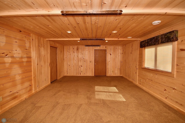 carpeted empty room with beamed ceiling, wooden walls, and wood ceiling