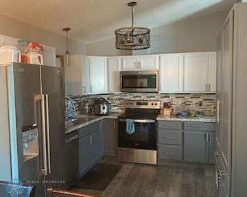 kitchen featuring white cabinets, stainless steel appliances, hanging light fixtures, and dark hardwood / wood-style flooring