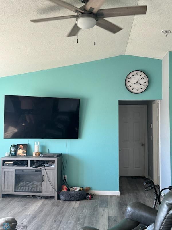 living room with a textured ceiling, vaulted ceiling, hardwood / wood-style floors, and ceiling fan