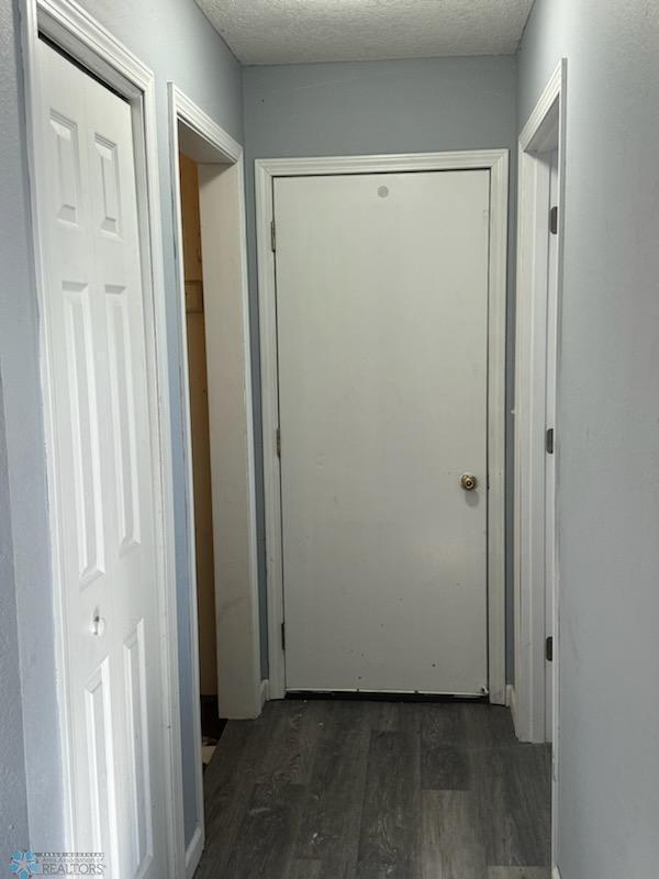 hall featuring a textured ceiling and dark hardwood / wood-style flooring