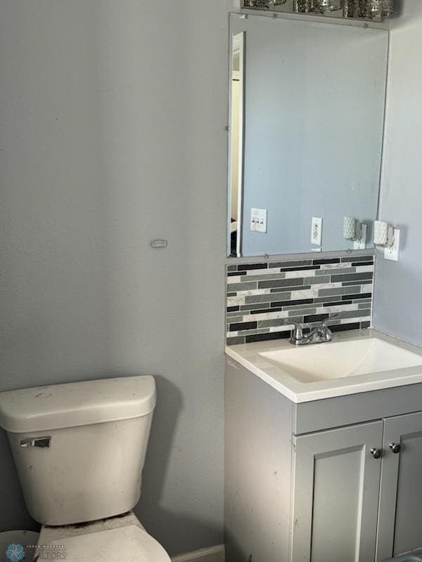 bathroom with backsplash, vanity, and toilet