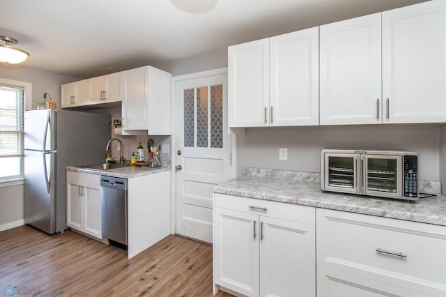 kitchen featuring stainless steel appliances, light wood-type flooring, sink, and white cabinetry