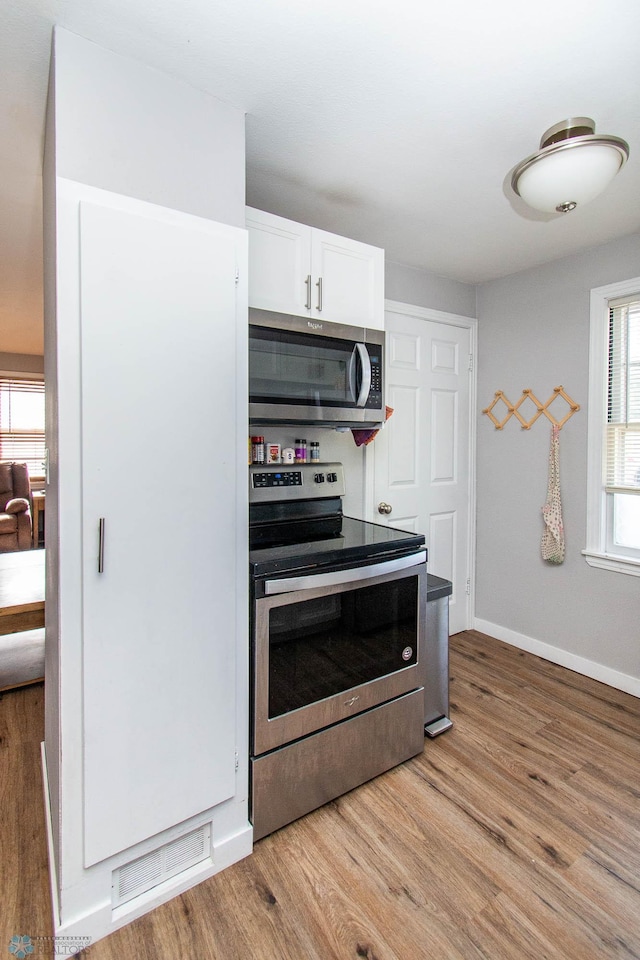 kitchen featuring light hardwood / wood-style flooring, stainless steel appliances, and white cabinets