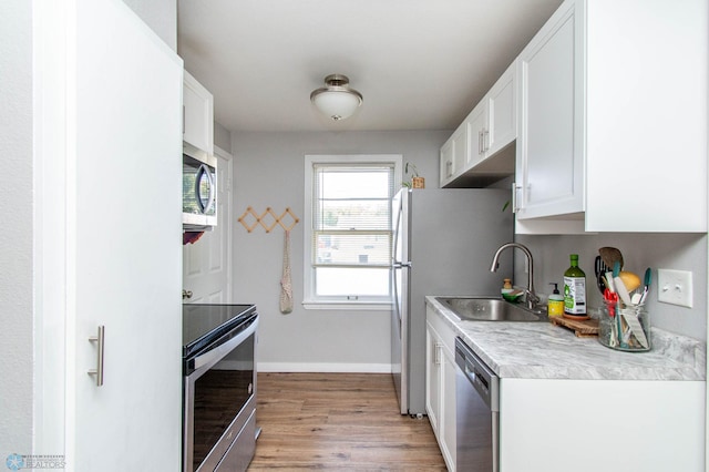 kitchen featuring appliances with stainless steel finishes, light wood-type flooring, sink, and white cabinets