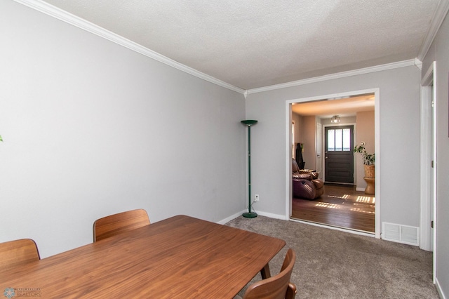 dining room featuring ornamental molding, carpet, and a textured ceiling