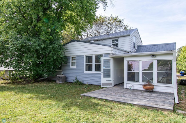 rear view of property featuring a deck, a yard, and a sunroom