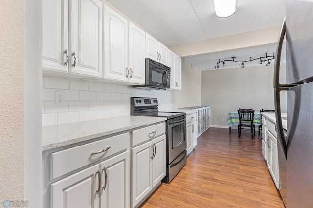 kitchen featuring decorative backsplash, light wood-type flooring, black appliances, and white cabinetry