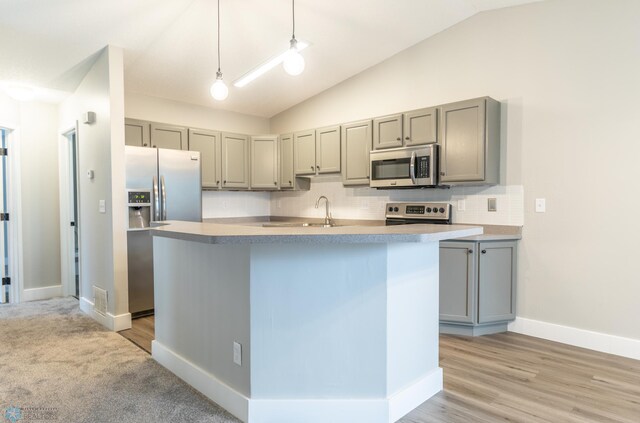 kitchen featuring tasteful backsplash, lofted ceiling, hanging light fixtures, gray cabinetry, and stainless steel appliances