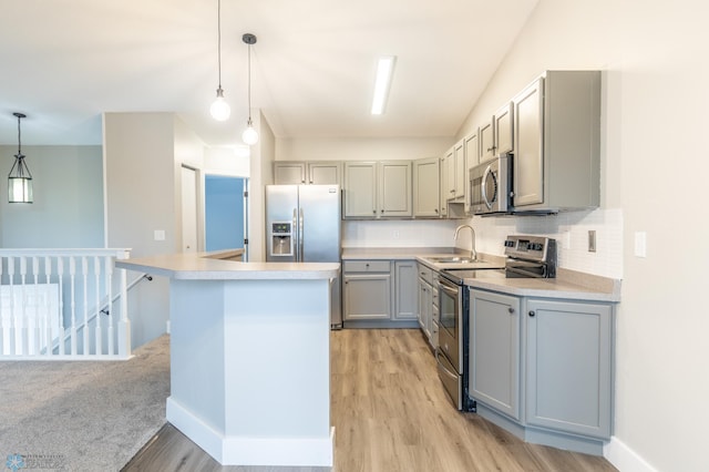 kitchen featuring hanging light fixtures, gray cabinets, stainless steel appliances, a center island, and light hardwood / wood-style flooring