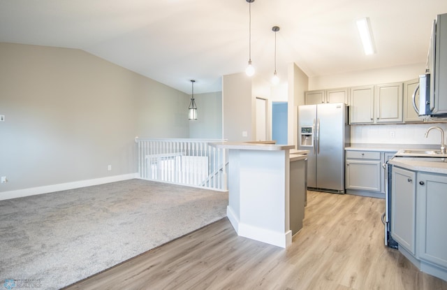 kitchen featuring stainless steel appliances, lofted ceiling, light hardwood / wood-style floors, and decorative light fixtures