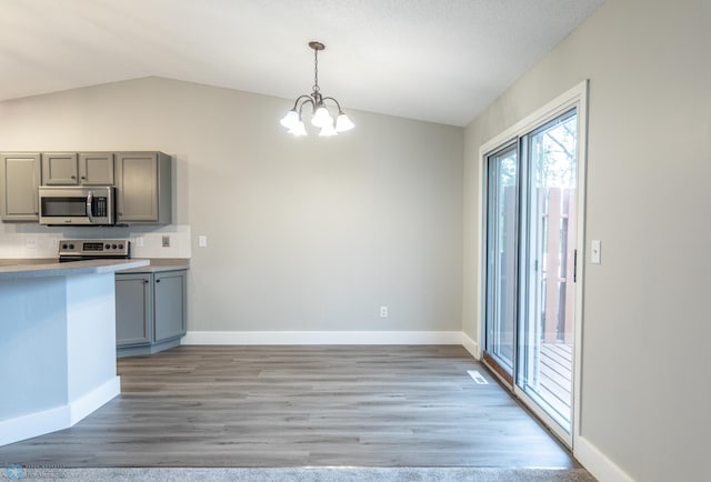 kitchen featuring light hardwood / wood-style flooring, lofted ceiling, appliances with stainless steel finishes, and decorative light fixtures