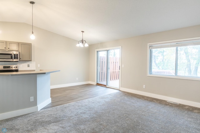 unfurnished living room featuring vaulted ceiling, dark wood-type flooring, and a notable chandelier