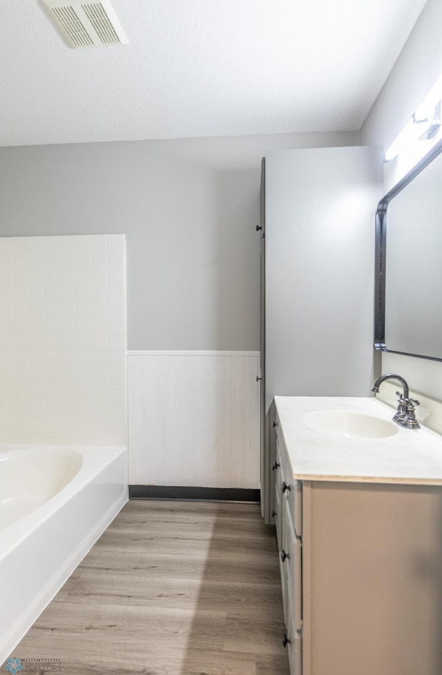 bathroom with wood-type flooring, vanity, and a bath