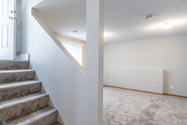 stairway featuring carpet and a textured ceiling