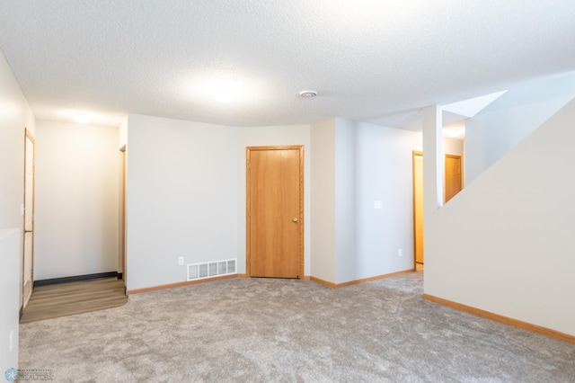 empty room featuring a textured ceiling and light colored carpet