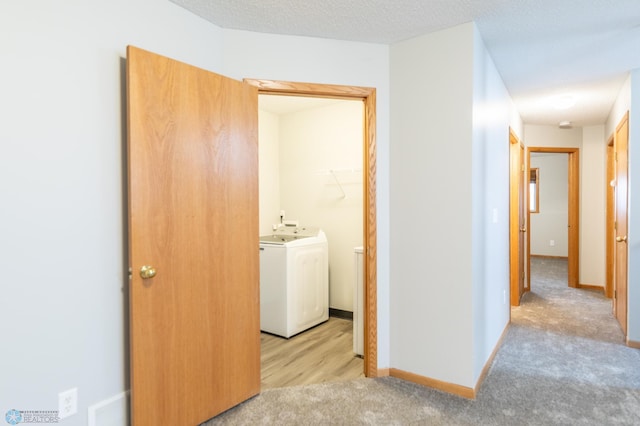 interior space featuring washer / clothes dryer, a textured ceiling, and light colored carpet