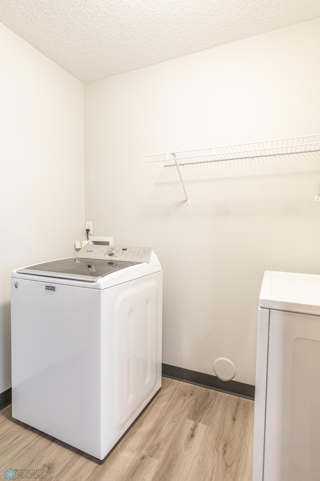 laundry area featuring a textured ceiling, light hardwood / wood-style floors, and hookup for a washing machine