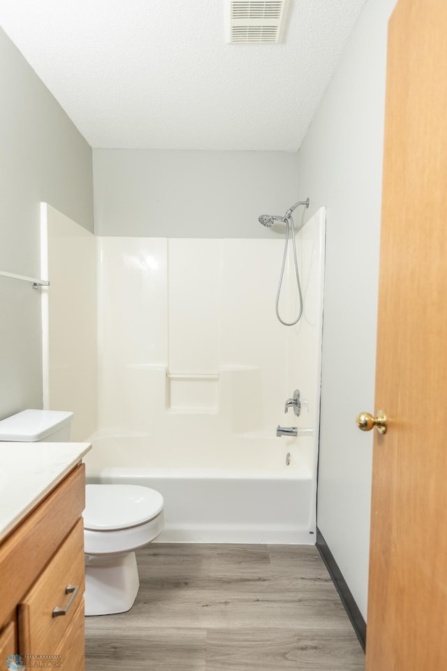 full bathroom featuring wood-type flooring, a textured ceiling,  shower combination, vanity, and toilet