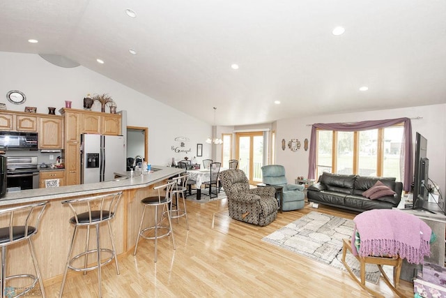 living room with light hardwood / wood-style flooring, vaulted ceiling, a notable chandelier, and sink