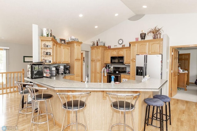 kitchen with light brown cabinets, a breakfast bar, white refrigerator with ice dispenser, stainless steel electric stove, and vaulted ceiling