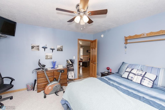 carpeted bedroom featuring ceiling fan and a textured ceiling