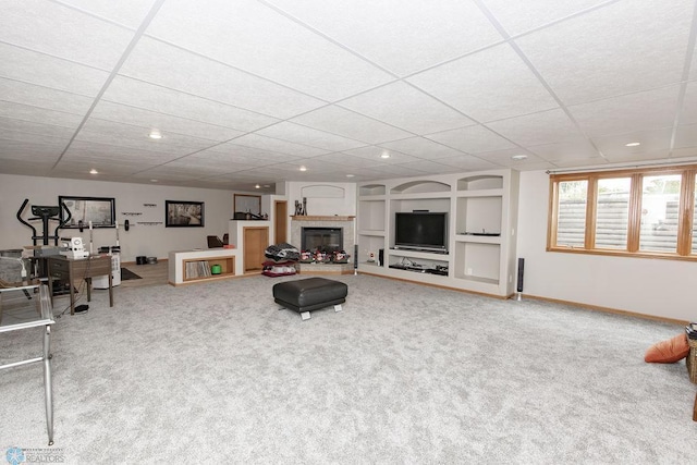 living room featuring built in shelves, carpet floors, and a paneled ceiling