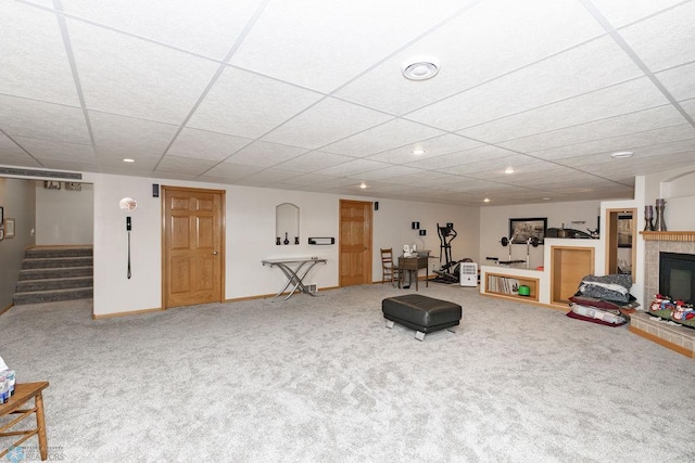 exercise room with carpet floors, a fireplace, and a drop ceiling