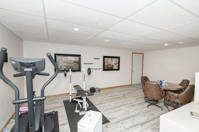 exercise room featuring light wood-type flooring and a paneled ceiling