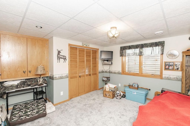 carpeted bedroom with a paneled ceiling and a closet