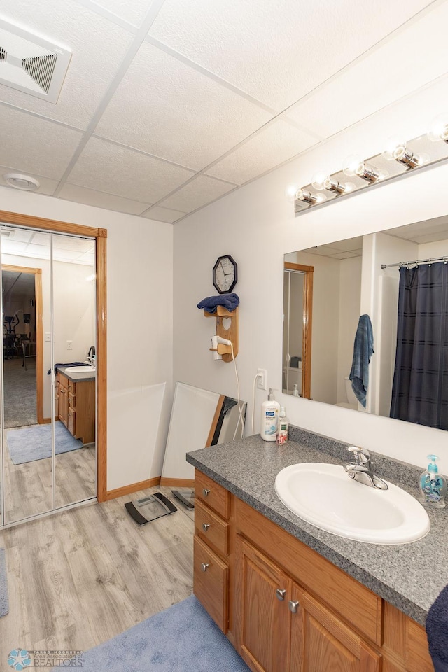 bathroom featuring wood-type flooring, a drop ceiling, vanity, and plus walk in shower