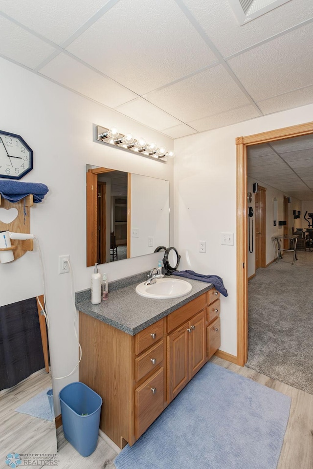 bathroom with vanity, a drop ceiling, and hardwood / wood-style flooring