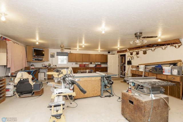 kitchen featuring ceiling fan, a textured ceiling, and a center island