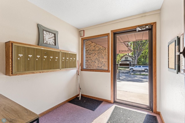 doorway to outside featuring a textured ceiling and a mail area