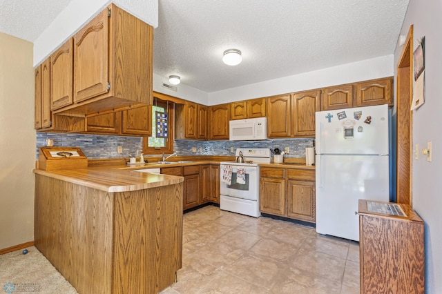 kitchen featuring a textured ceiling, decorative backsplash, white appliances, and kitchen peninsula