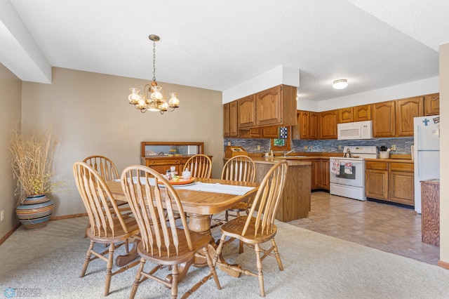 carpeted dining area with a textured ceiling, an inviting chandelier, and sink