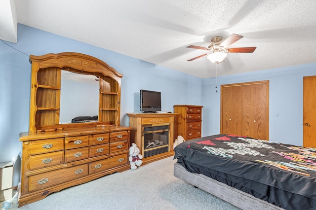 bedroom with ceiling fan, a textured ceiling, a closet, and carpet flooring