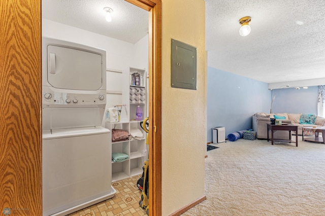 laundry room featuring light carpet, electric panel, stacked washer / drying machine, and a textured ceiling